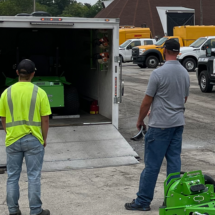 Landscaping crew reviewing equipment in trailer while holding a checklist for end-of-season preparations and gearing up for a successful year ahead.