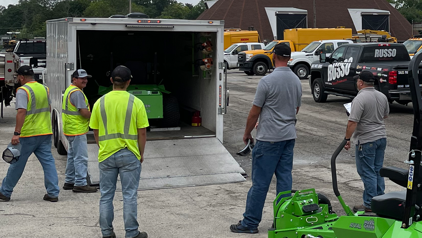 Landscaping crew reviewing equipment in trailer while holding a checklist for end-of-season preparations and gearing up for a successful year ahead.